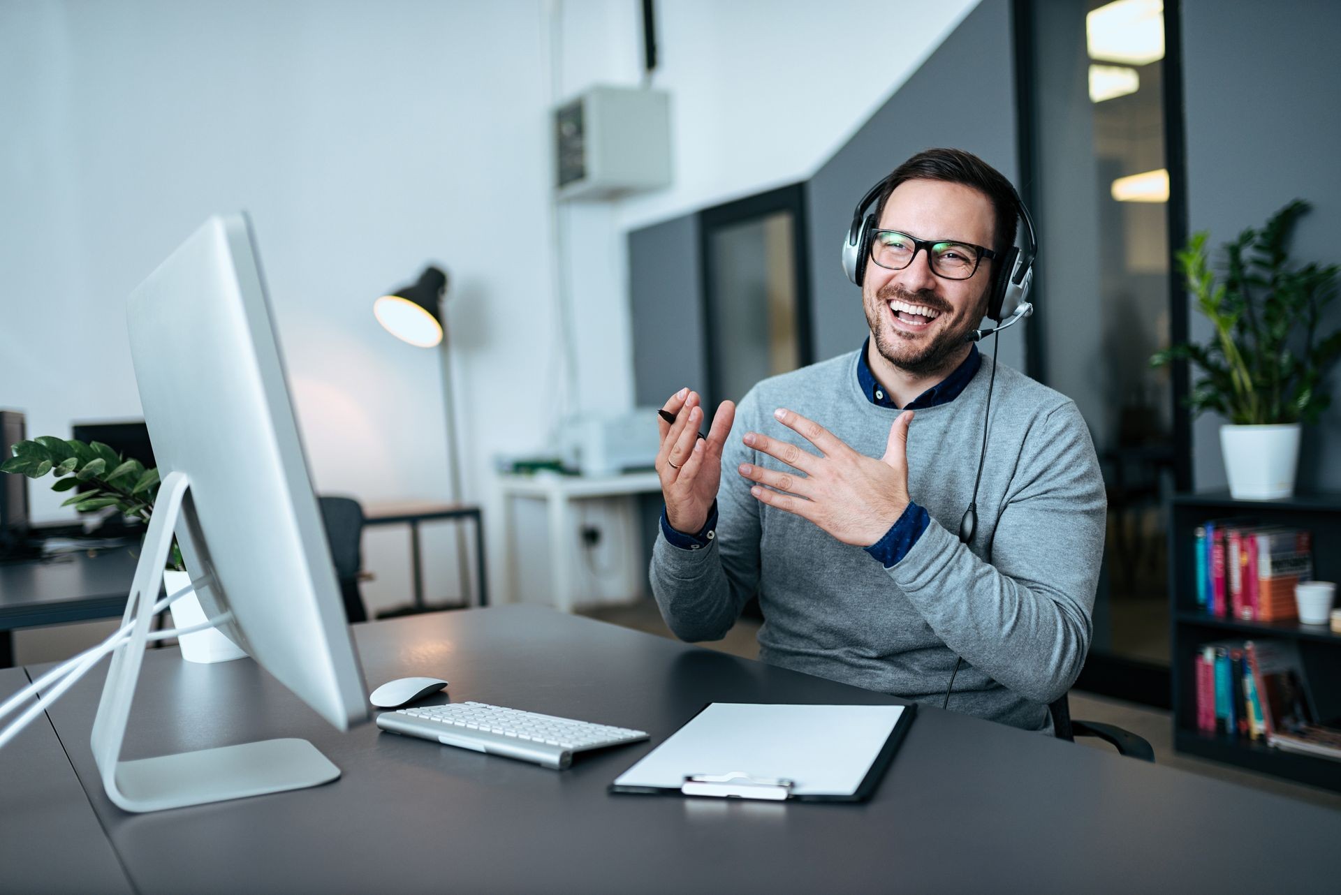 Happy young customer service operator talking via headset in modern office.